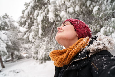 Low angle view of woman standing against snow covered tree during winter