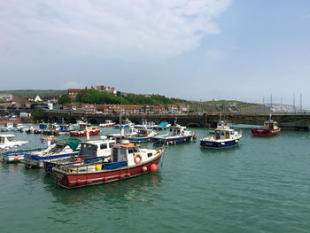 Boats moored at harbor against sky