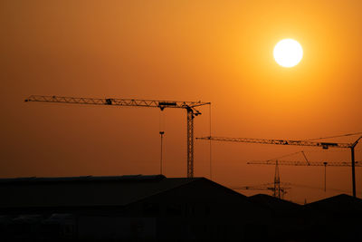 Low angle view of silhouette crane against sky during sunset