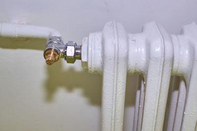 Close-up of water drop from faucet against white wall