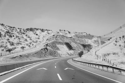 Road passing through mountains against clear sky