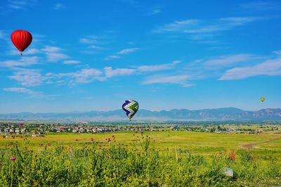 Hot air balloon flying over field against sky