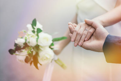 Midsection of couple holding flower bouquet