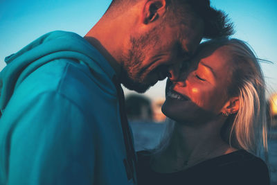 Close-up of couple embracing against blue sky
