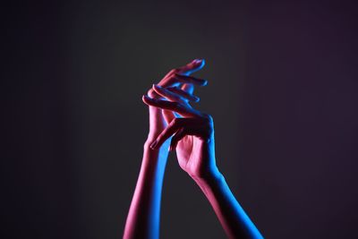 Close-up of hand holding illuminated lighting equipment against black background