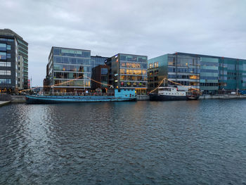 Buildings by river against sky