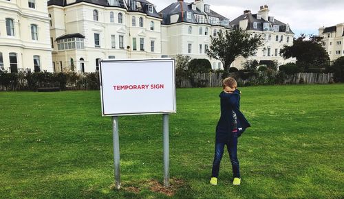 Full length of woman standing on field against building