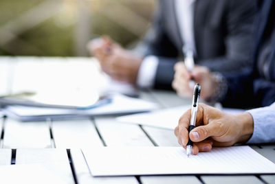 Cropped image of businessman writing on document at table