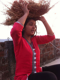 Beautiful young woman with arms raised against wall