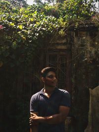 Young man standing against trees