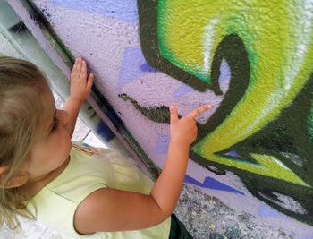 Rear view of woman against graffiti wall