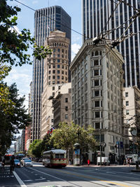 City street by modern buildings against sky