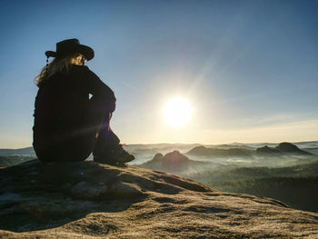 Cute light hair woman enjoying the outdoors at the mountain. sports figure sit on rough rocky ground