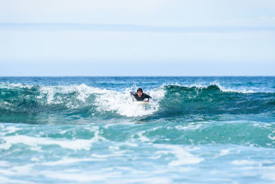 Man surfing in sea against sky