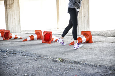 Low section of woman running by traffic cones on footpath