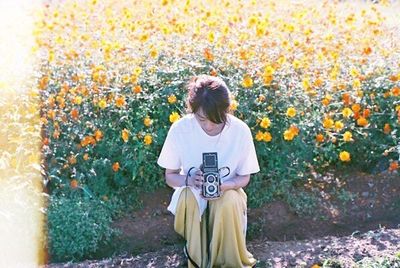 Rear view of woman standing on yellow flowering plants
