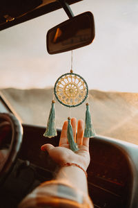 Midsection of man holding dream catcher in car