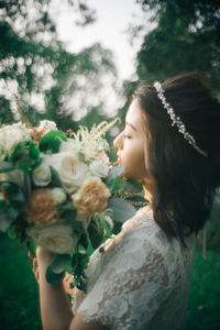 Close-up of woman with bouquet against trees