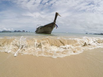 Close-up of wave with boat anchored at beach