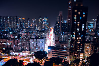 Miniture hk. high angle view of illuminated buildings in city at night with tilt lens