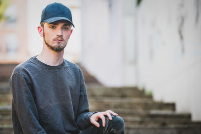 Portrait of young man wearing cap while sitting on steps