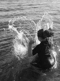 Rear view of girl splashing water in sea