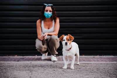 Full length of woman with dog against shutter