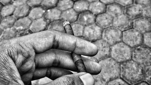 Close-up of human hand holding cigarette on footpath