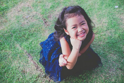 Portrait of smiling girl on grassy field at public park