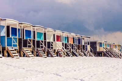 Hooded chairs on beach against sky