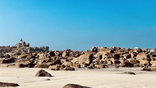 Scenic view of rocky beach against clear blue sky