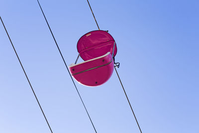 Low angle view of red flags hanging against clear blue sky