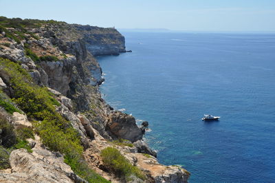 High angle view of cliff by sea against clear sky