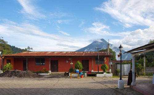 Building by mountain against cloudy sky