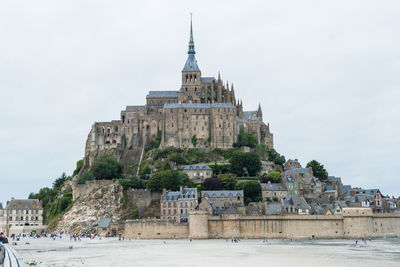 Castle at beach against cloudy sky