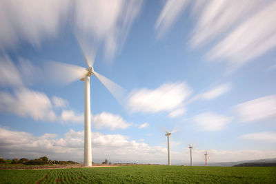 Wind turbines on field against sky