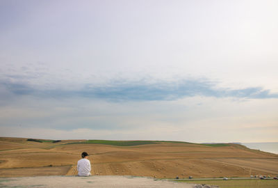 Rear view of man standing on land against sky