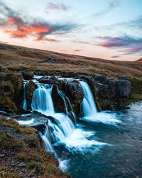 Scenic view of waterfall against sky during sunset