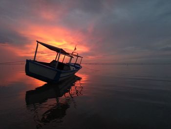 Fishing boat on sea against sky during sunset