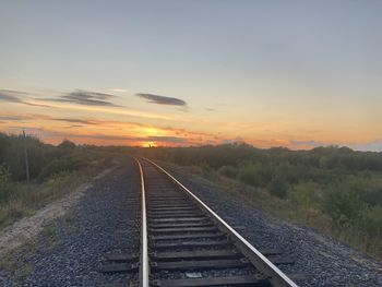 Railroad tracks against sky during sunset