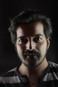 Portrait of young man against black background