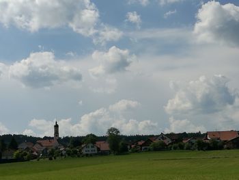 Houses on field against cloudy sky