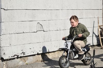Full length of boy riding bicycle against wall