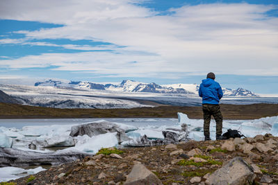 Rear view of man standing on snowcapped mountain