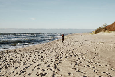 Rear view of woman on beach against sky