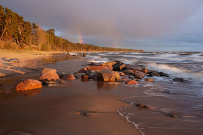 Rocks on beach against sky during sunset