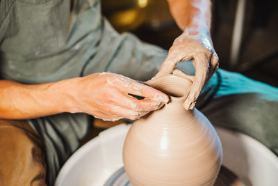 Cropped hands of potter making pot in pottery workshop