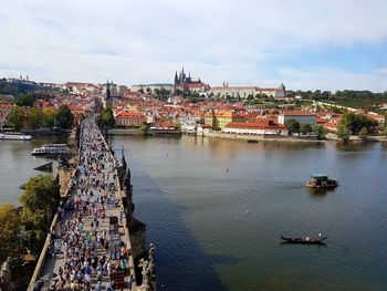 People on footbridge over river in city