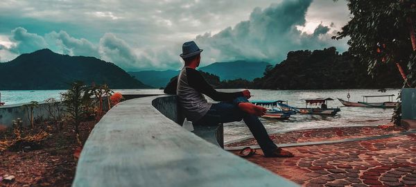Man sitting on boat in sea against sky