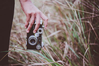 Midsection of woman holding camera on field